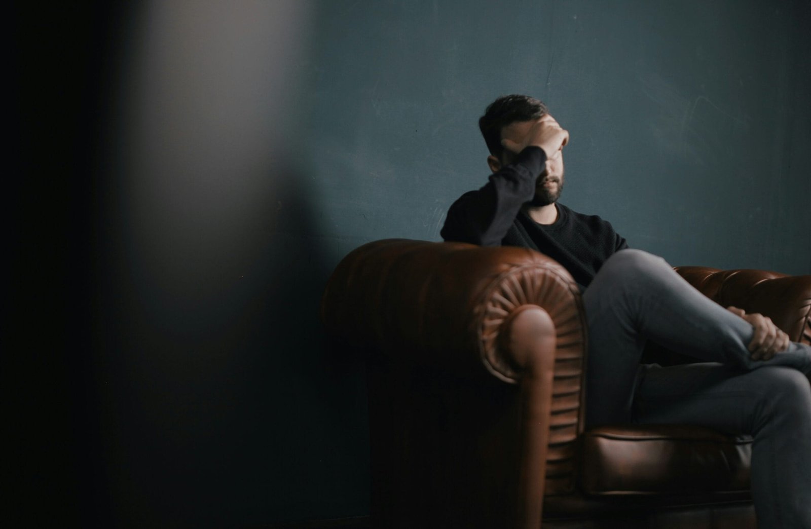 Managing Anxiety in Daily Life 1 a man holds his head while sitting on a sofa